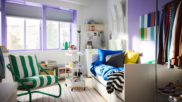 Bedroom with big windows with sash painted purple, a white daybed, a trolley on wheels and green/white ÖNNESTAD armchair.